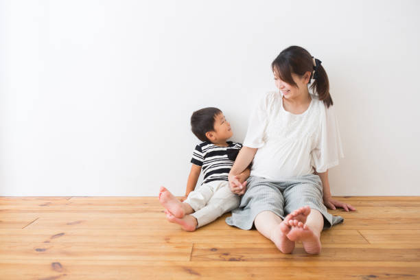 男の子と妊娠中の女性は、床に座っている人 - 純真 ストックフォトと画像