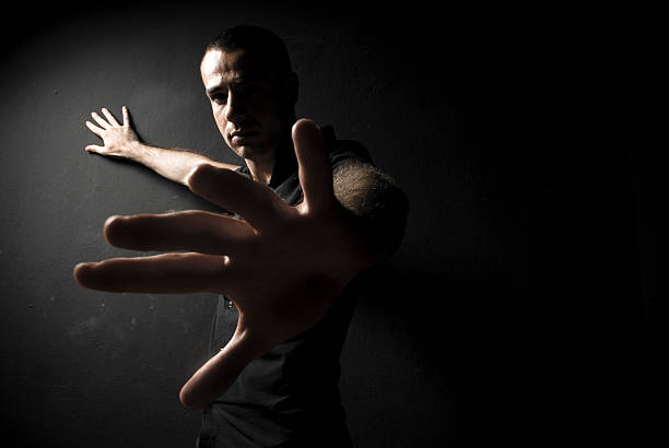 Male model posing in front of a black wall.