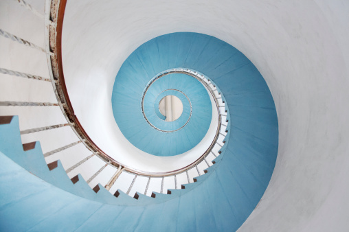 Top-view photo of a spiral staircase. Forms a nautilus-shaped abstract pattern.