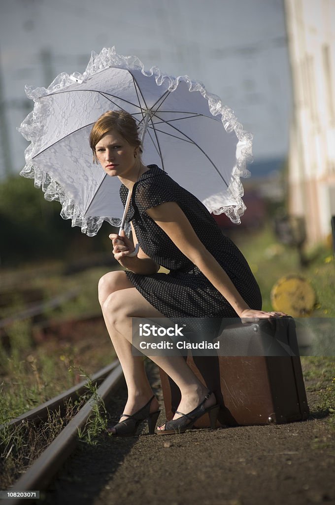Woman Sitting on Luggage Near Train Tracks and Carrying Parasol  1920-1929 Stock Photo