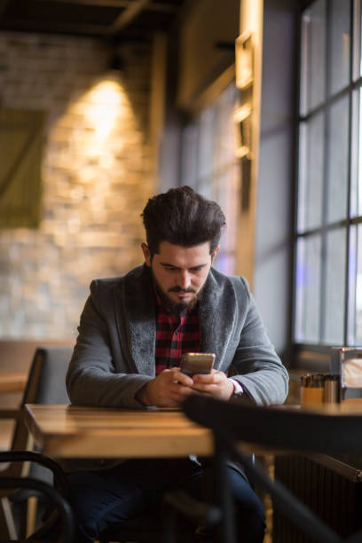 istock Happy hipster man at coffee shop texting on mobile phone 1082031496