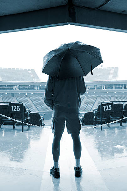 Uomo con ombrello in piedi all'ingresso di Sport Stadium - foto stock