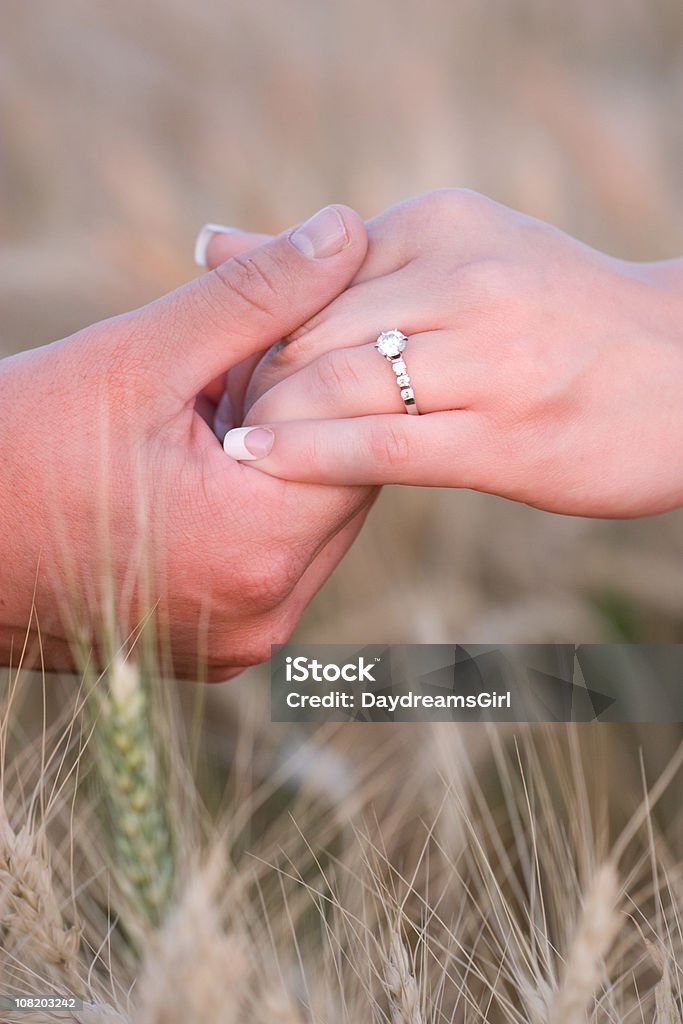 Hombre que agarra mano de mujer con diamante anillo de compromiso en campo - Foto de stock de Anillo - Joya libre de derechos