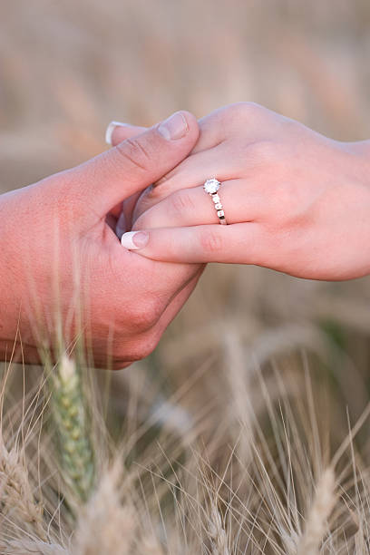 istock Man Holding Woman's Hand with Diamond Engagement Ring in Field 108203242