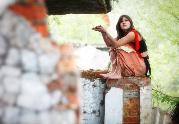 Young woman standing alone at ruins in the forest