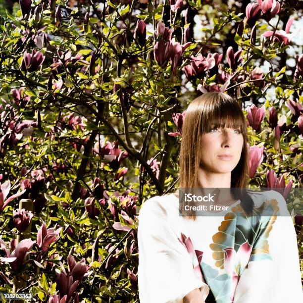 Jovem De Pé Perto Da Árvore Com Flores - Fotografias de stock e mais imagens de Adulto - Adulto, Alta Costura, Ao Ar Livre