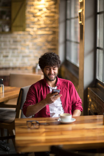 istock Happy hipster man at coffee shop texting on mobile phone 1082035358