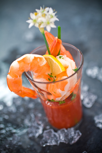 This is a close up photograph of individual shrimp cocktails ready to eat on a table outdoors during the day.