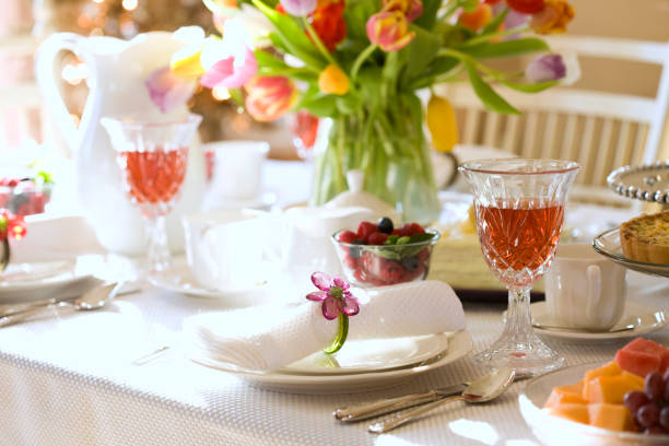 Place setting in soft focus, with delicate peach flower.  shallow depth of field.  More place settings and cutlery:
