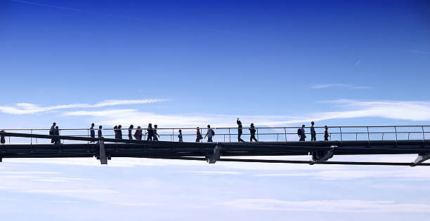 Man with backpack walking along a curve, modern structure, view from below on the blue sky