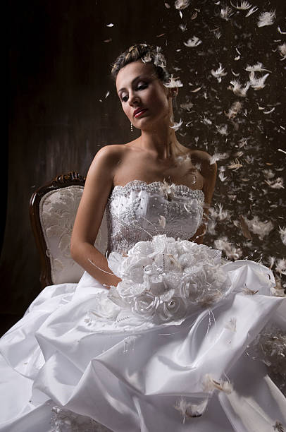A bride dreaming while she is sitting on an old style chair.