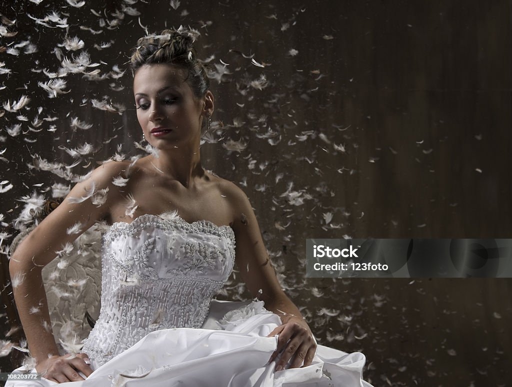 Noiva sentado na cadeira com penas flutuando ao redor dela - Foto de stock de Vestido de Noiva royalty-free