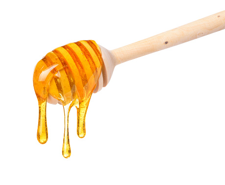 Rich honey dripping from wooden dipper spoon isolated on white background