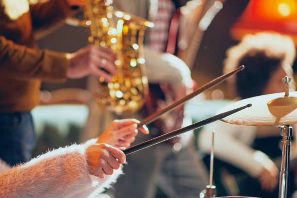 Close up of Caucasian woman holding drumsticks and playing drums. Home studio interior.