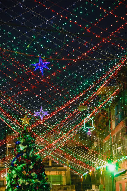 KOLKATA, WEST BENGAL, INDIA - DECEMBER 24TH 2017 : A big christmas tree is illuminated with lights at Bow Barracks - a famous Anglo-Indian street of Kolkata, at night. Decorative lights overhead.