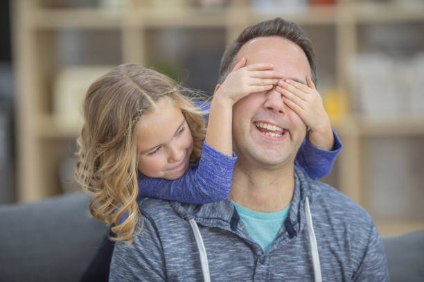 istock Little girl covering her dad's eyes 1082065272