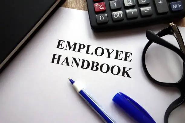 Employee handbook, pen, glasses and calculator on desk