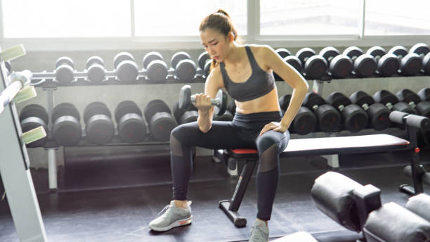 istock Young Woman Exercising With Dumbbell In Gym 1082071188