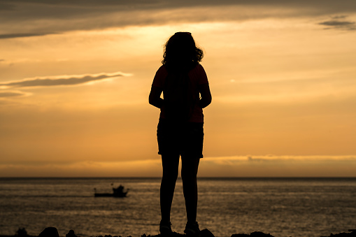 Silhouette of a young woman on the rocks