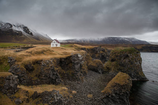 istock Famous building under the Snaefellsjokull volcano and glacier in Arnarstapi, Snaefellsnes peninsula, Iceland. Dramatic icelandic landscape, lonely house on the volcanic cliffs seacoast. Icelandic land 1082091574