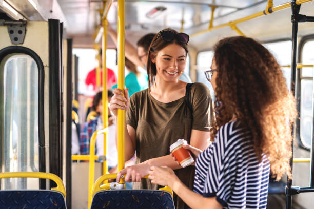 glücklich multikulturellen teenager im chat und stehend in den stadtbus. - öffentliches verkehrsmittel stock-fotos und bilder