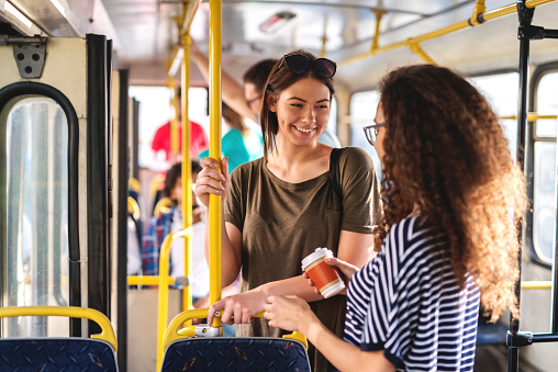 Felizes multiculturales adolescentes chateando y de pie en el autobús de la ciudad. photo