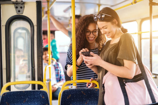 istock Two girls watching phone and standing in a public transportation. 1082096674