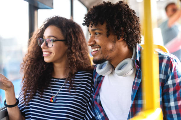 istock Smiling multicultural couple sitting on the city bus and looking through window. 1082098270