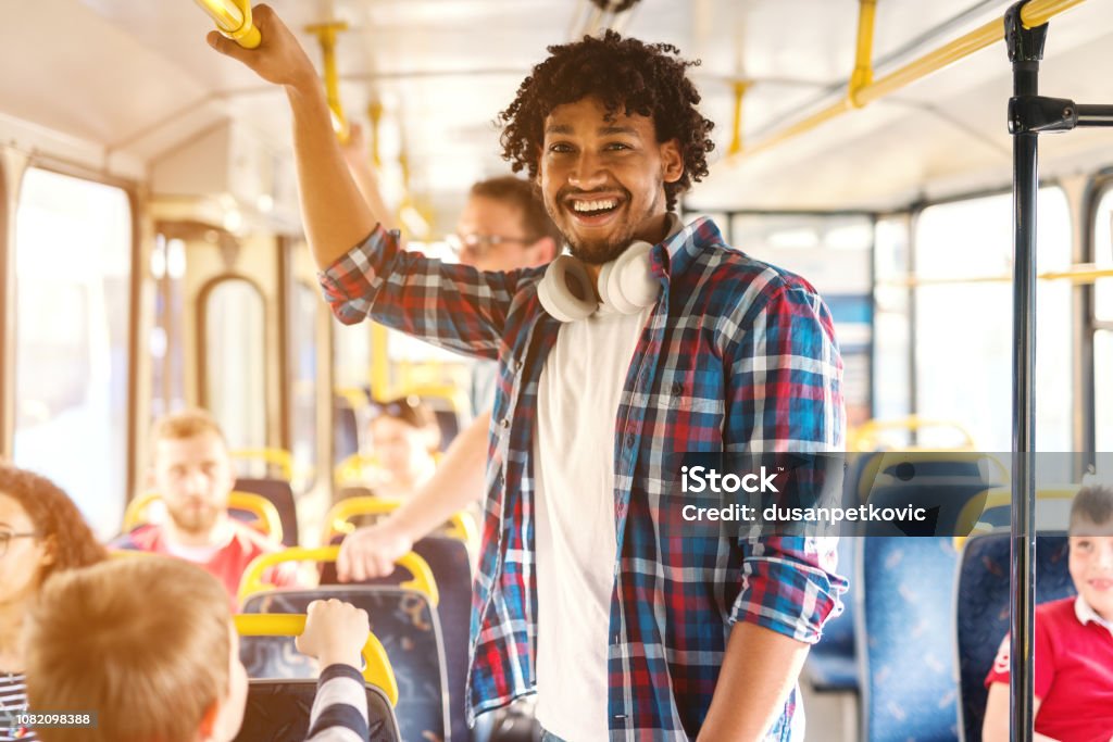 Young smiling African American man riding in the city bus and looking at camera. Bus Stock Photo