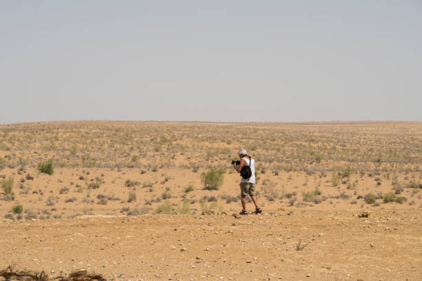 istock Senior man walking in desert with camera 1082098480