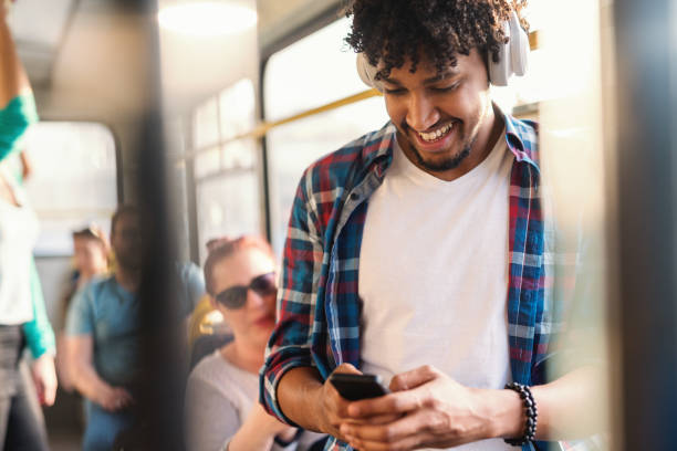 istock Young African guy listening to the music and using smart phone while riding in public transportation. 1082102100
