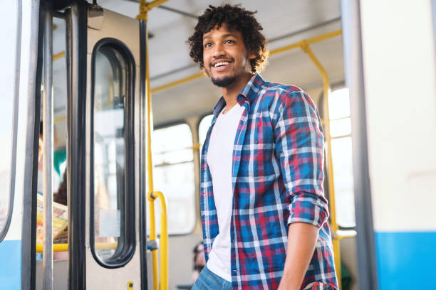 młody uśmiechnięty afroamerykanin wysiadając z autobusu. - disembarking zdjęcia i obrazy z banku zdjęć