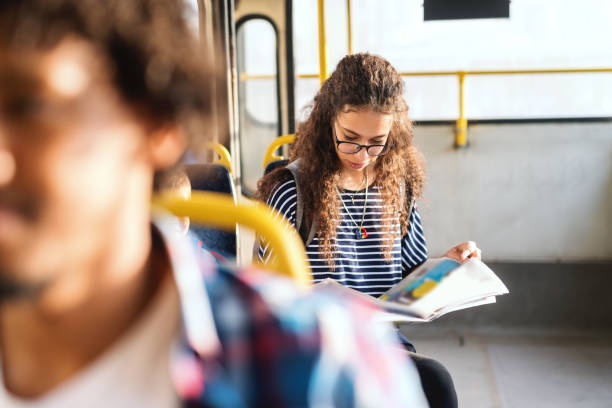 istock Mixed race girl reading newspaper and sitting while waiting bus to start. Image focus technique. 1082105268