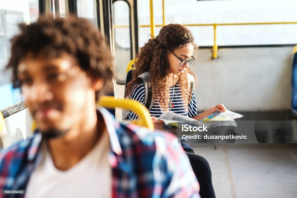 Young women reading newspaper and sitting while waiting bus to start. Image focus technique. Newspaper Stock Photo