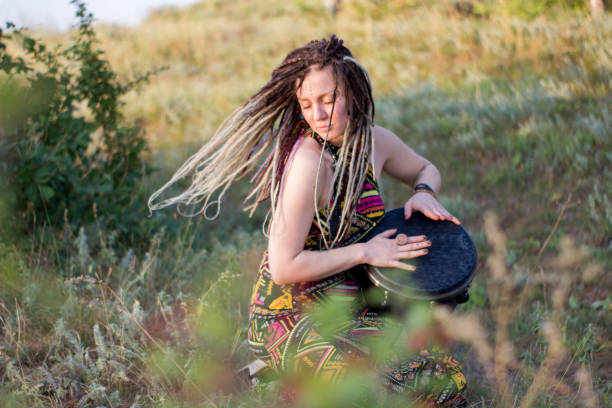 chamán de hippie de hermosa mujer joven tocando djembe y bailando danzas salvajes al atardecer - mistic fotografías e imágenes de stock