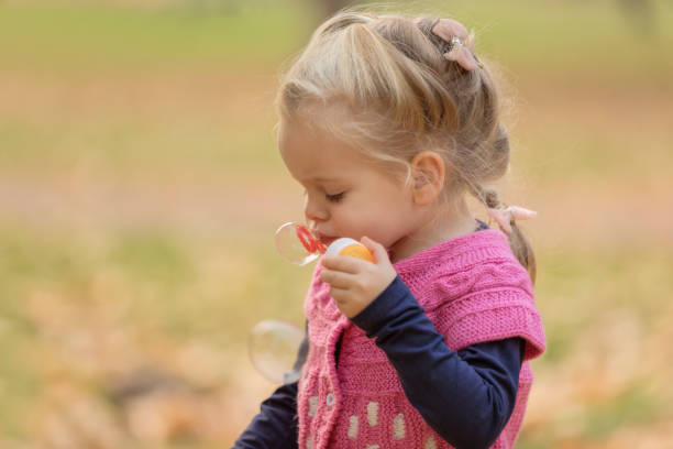 istock Charming little girl blowing soap bubbles 1082144154