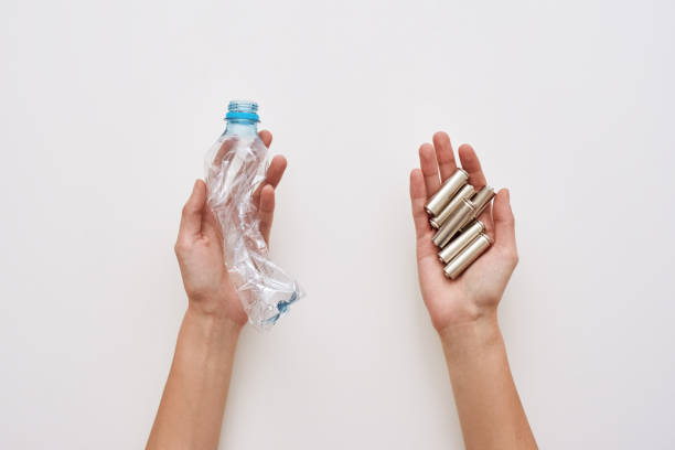 istock Sparate your trash. Two human hands are holding plastic and batteries isolated 1082166958