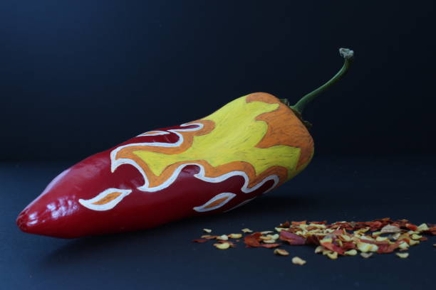 istock Red Chilli Pepper With Painted Fire On Black Craft Paper Background 1082176000