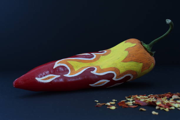istock Red Chilli Pepper With Painted Fire On Black Craft Paper Background 1082176004