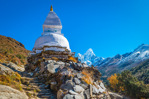 Traditional white-washed Buddhist stupa and mani stones high in the thin mountain air above the Khumbu valley overlooked by Ama Dablam (6812m) deep in the remote Himalayan wilderness of the Sagarmatha National Park, a UNESCO World Heritage Site, Nepal.