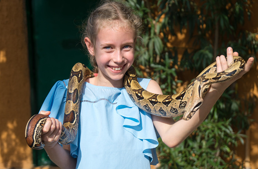 Cute little girl holding snake in her hands.