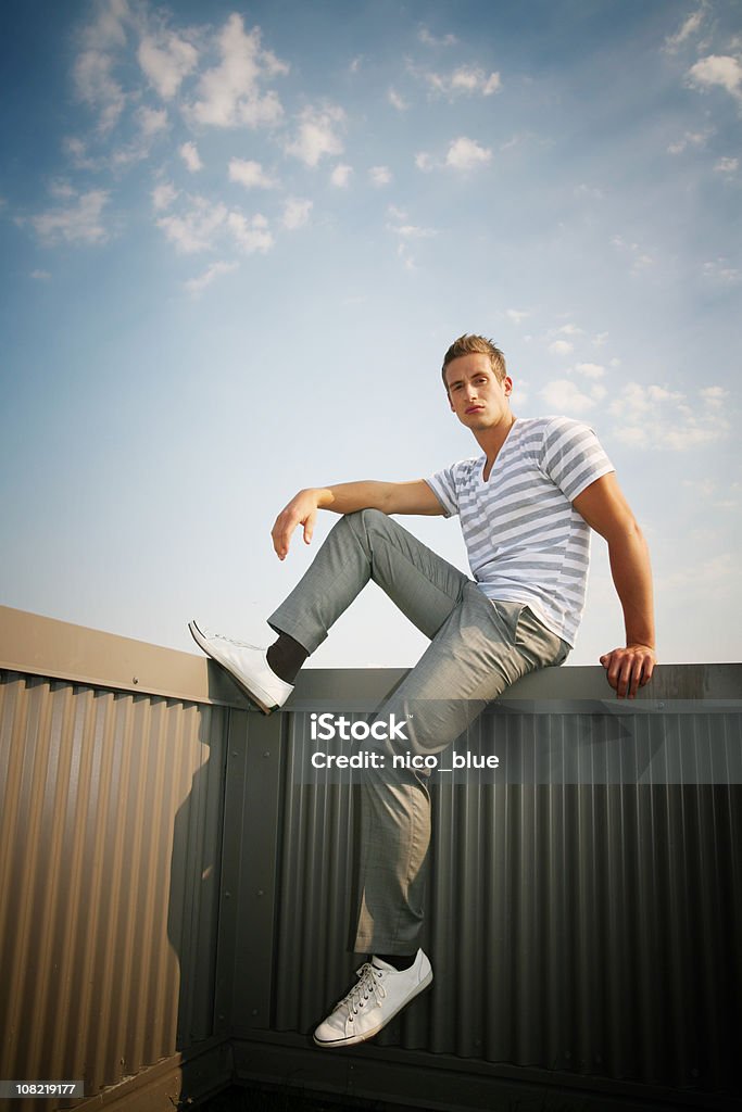 Trendige junger Mann sitzt auf dem Zaun - Lizenzfrei Porträt Stock-Foto