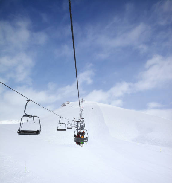 istock Chair-lift, snow ski slope and cloudy sky with falling snow 1082194528