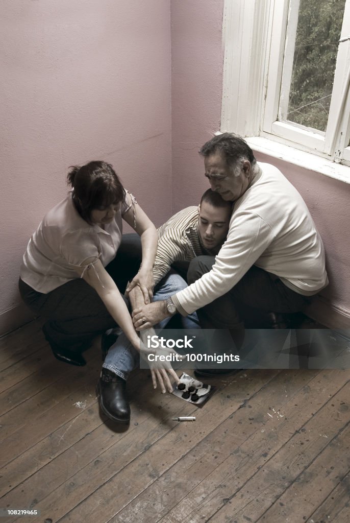 Two Parents Hold Young Man's Arm From Reaching Syringe  Addiction Stock Photo