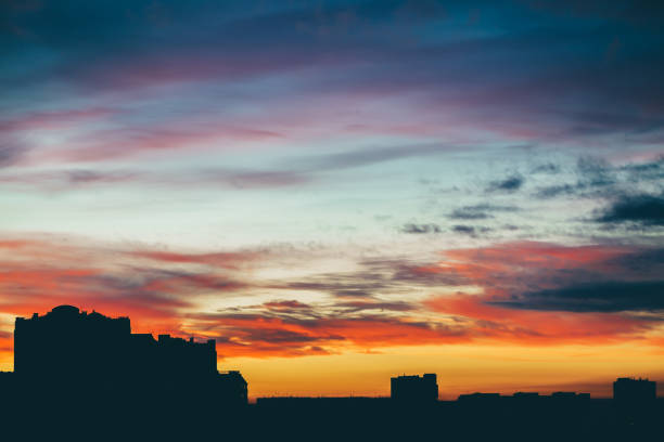 istock Cityscape with wonderful varicolored vivid dawn. Amazing dramatic multicolored cloudy sky above dark silhouettes of city buildings. Atmospheric background of sunrise in overcast weather. Copy space. 1082195232