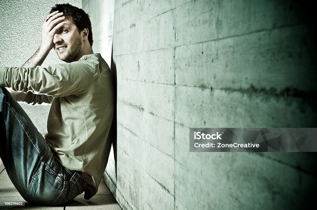 trouble man with problems sit on the floor against wall  Adult Stock Photo