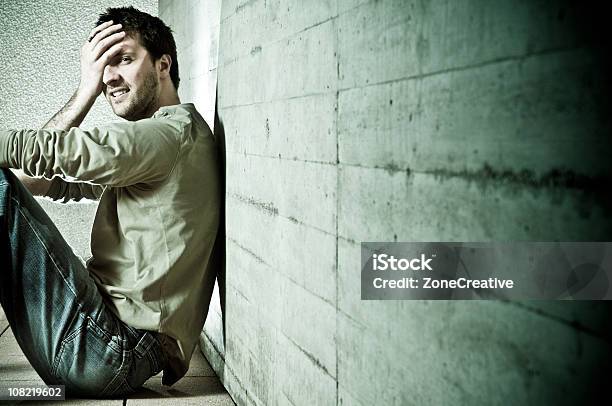 Trouble Man With Problems Sit On The Floor Against Wall Stock Photo - Download Image Now