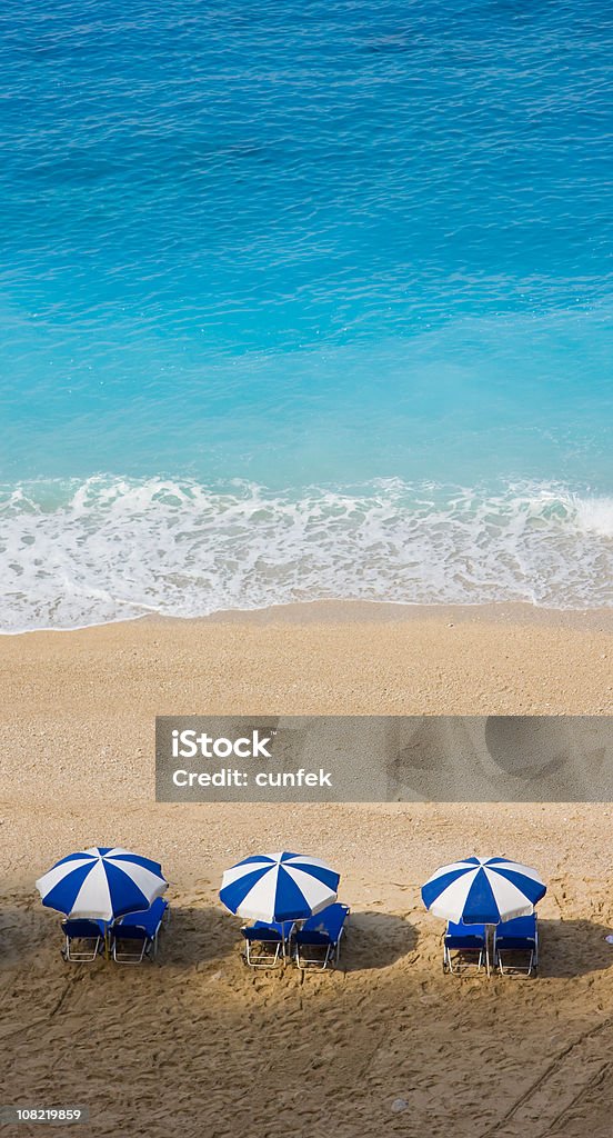 Azul y blanco sombrillas de playa de arenas blancas en agua - Foto de stock de Actividades recreativas libre de derechos