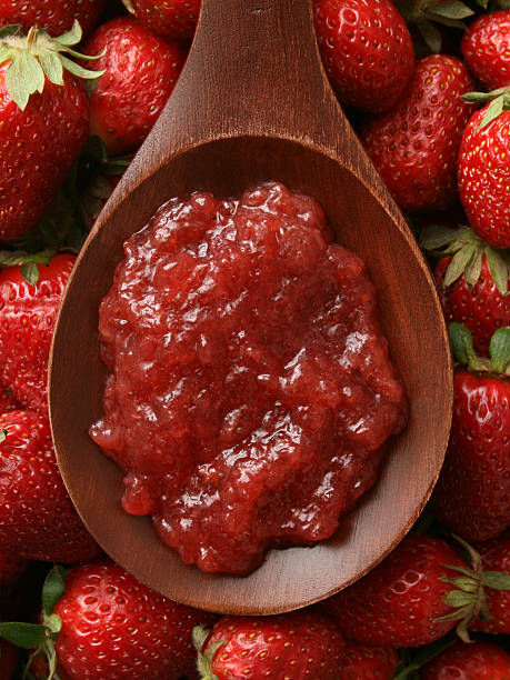 Top view of wooden spoon with strawberry jelly on it