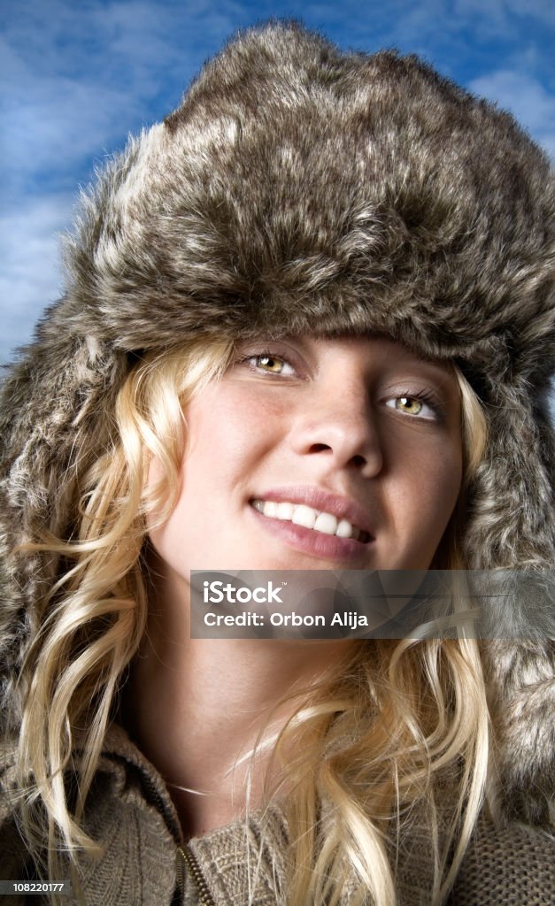 Giovane donna che indossa il cappello di pelliccia di inverno fuori contro il cielo blu - Foto stock royalty-free di Abiti pesanti